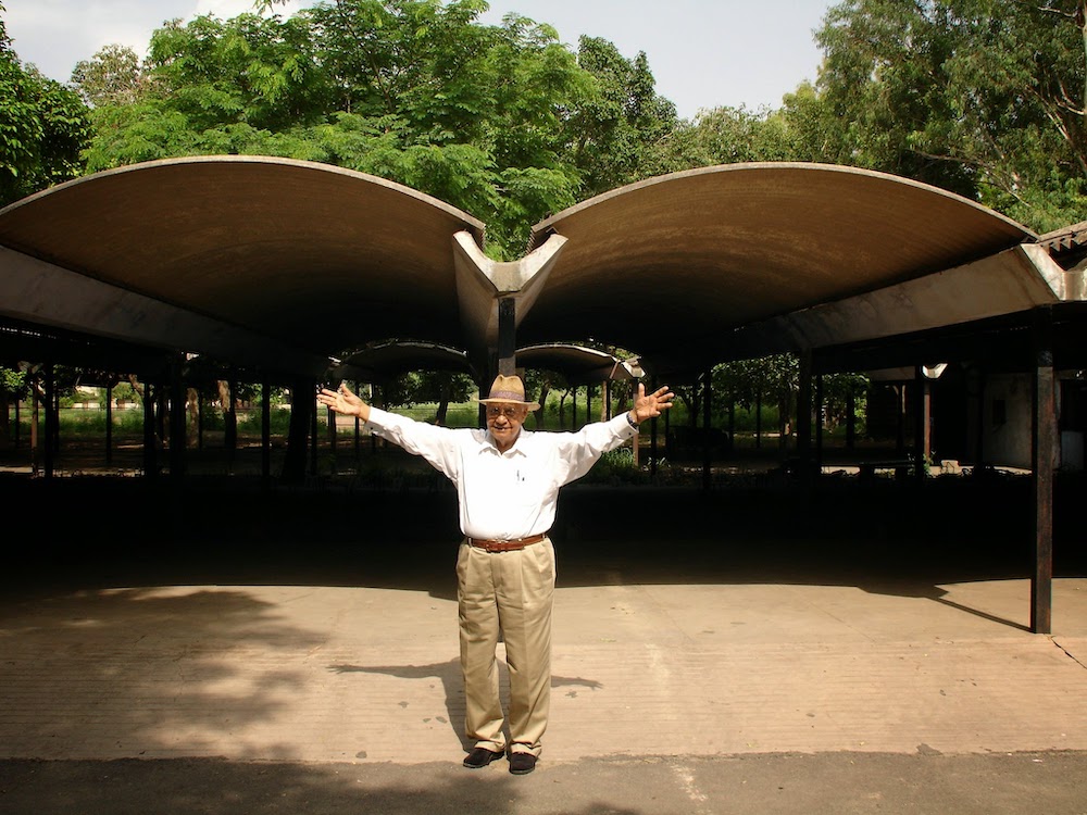 Aditya Prakash standing in front of a building with his arms stretched out wide in the air
