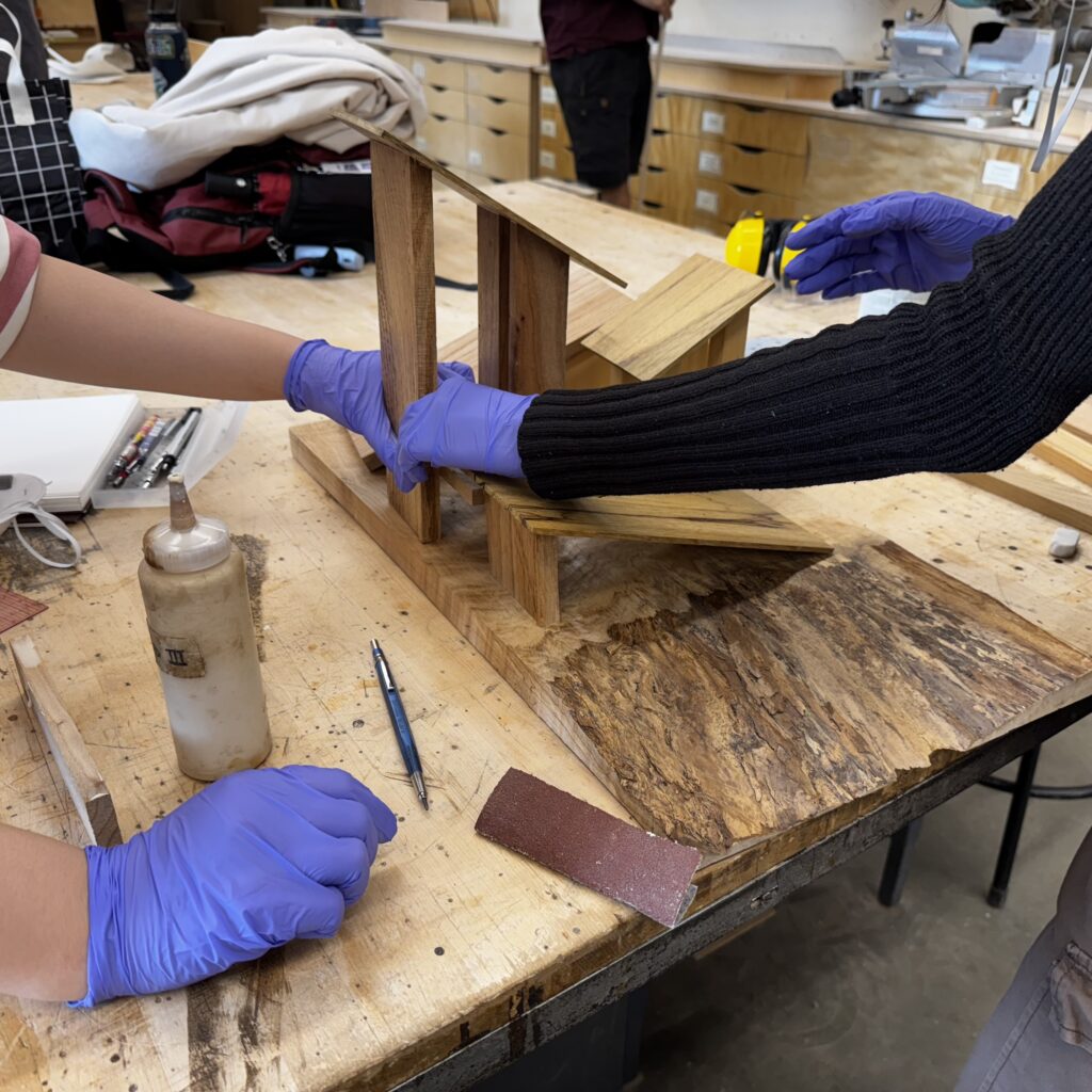 gloved hands of students building with wood