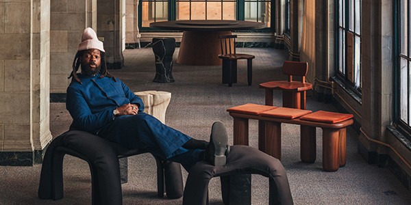 Designer Michael Bennett reclining with feet up on furniture he designed.